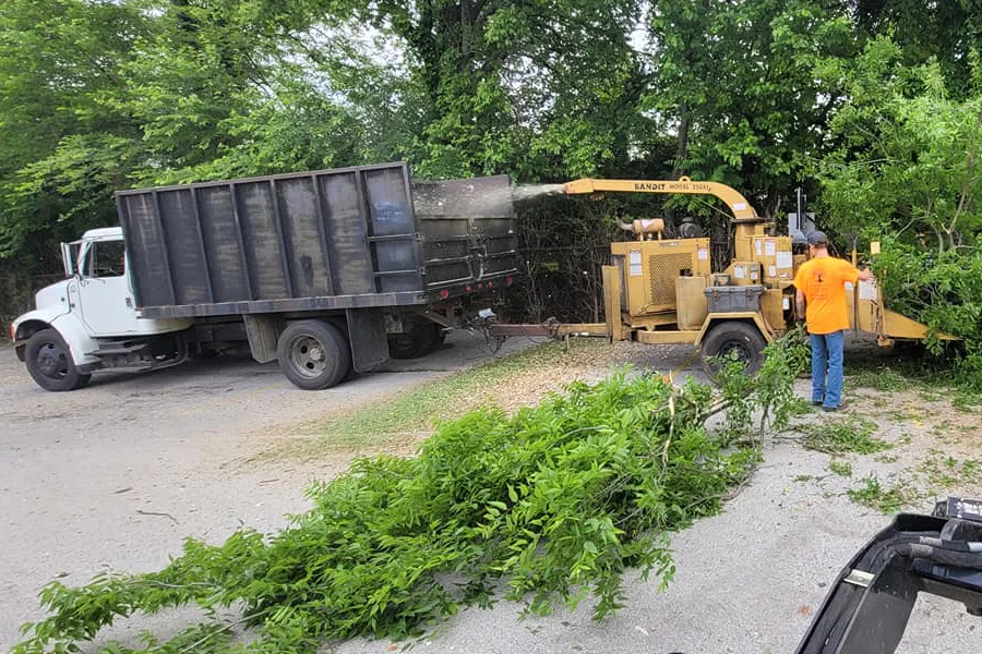 men putting tree branches through wood chipper salyserville ky